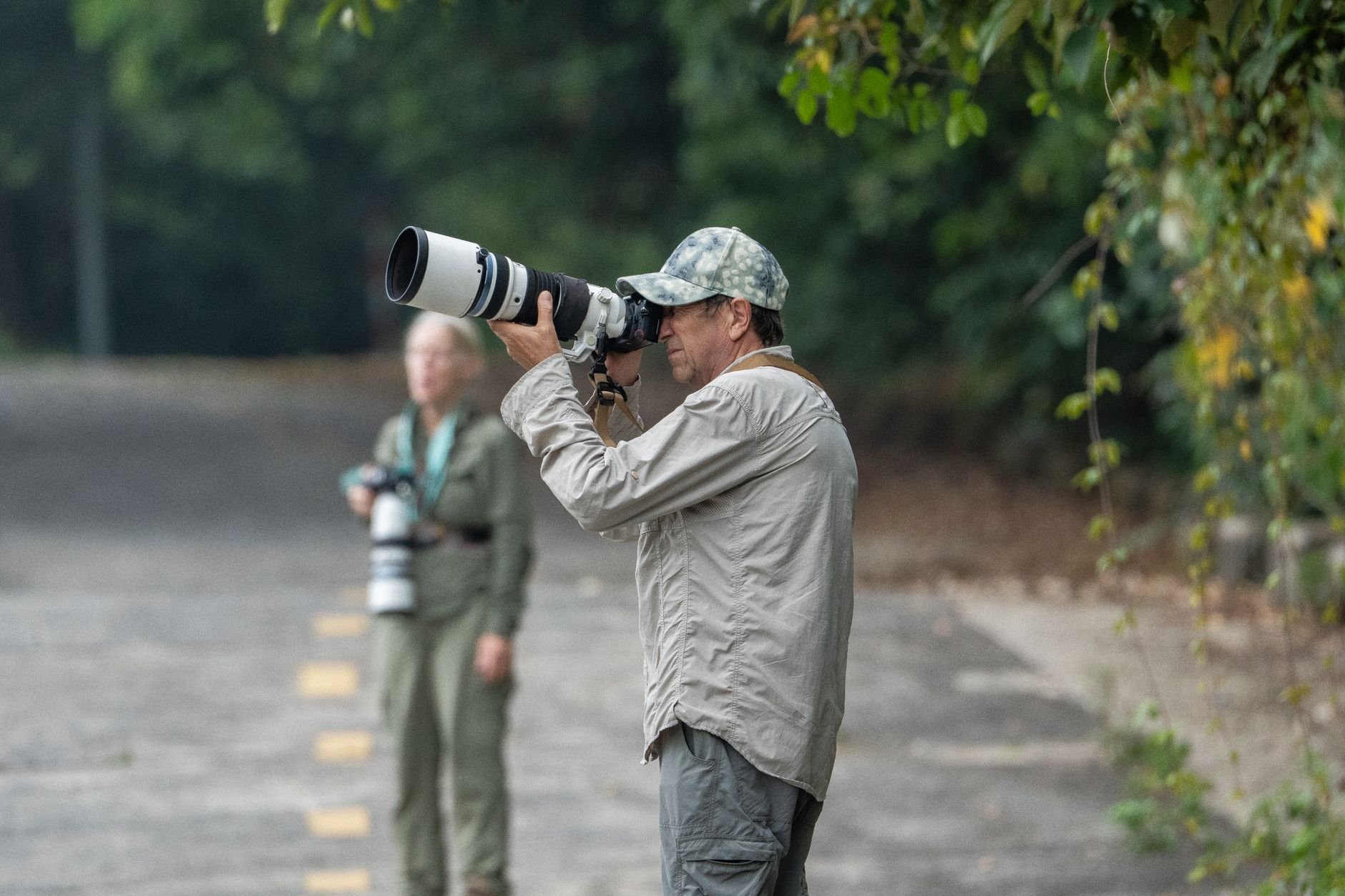 Two wildlife photographers with telephoto lenses in the field capturing nature
